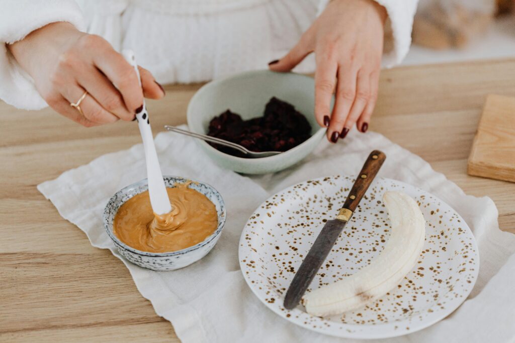 Preparing a healthy snack with peanut butter, banana, and berries, perfect for a nutritious lifestyle.